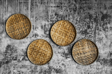 Gray shabby concrete wall decorated with wicker handmade round trays. Eco style and concept, Moroccan culture. Hipster cafe design.