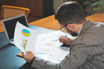 Young businessman studying diagrams in his personal office.