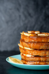 French toast with banana and homemade honey with cinnamon, dessert Breakfast on a blue plate on a dark background. the process of pouring honey into pieces of a stack of toast.