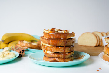 French toast with banana and homemade caramel with cinnamon, Breakfast dessert on a blue plate on a light background