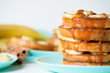French toast with banana and homemade caramel with cinnamon, Breakfast dessert on a blue plate on a light background