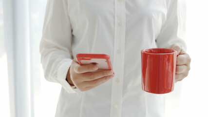 woman standing with a cup of red coffee and a smartphone