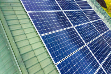 Obraz premium Aerial top view of new modern residential house cottage with blue shiny solar photo voltaic panels system on roof. Renewable ecological green energy production concept.