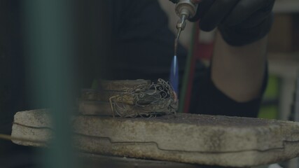Jeweler makes jewelry of silver. The jeweler to melt silver, makes patterns on it, grinds, cuts and drills. work gas torch