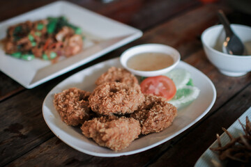 Fried shrimp cake,Thai food name is Tod Mun Goong eat with sweet sauce served on white dish in restaurant.