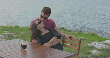 Couple in love sitting by the marina near the sea. Admire the scenery, hug, kiss, talk to each other and have fun