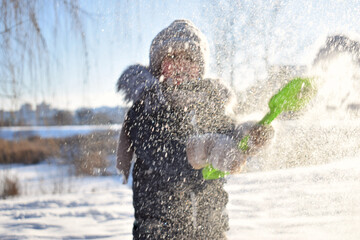 Baby boy walking at snowfall. Child in winter clothes playing with snow