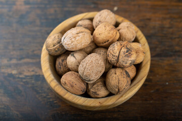 Walnut in wooden bowl on black background with copy space.