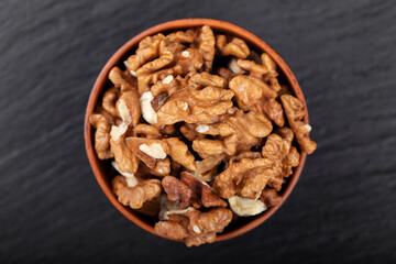 Walnut in clay bowl on black background with copy space.