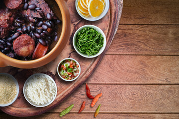 Feijoada. Traditional Brazilian food. Ceramic bowl isolated on rustic wooden background. Top view.