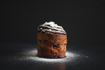 Easter cake kraffin sprinkled with icing sugar on a black background. Holiday baking. Easter traditions.