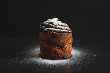 Easter cake kraffin sprinkled with icing sugar on a black background. Holiday baking. Easter traditions.
