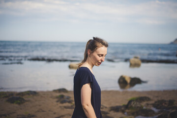 a woman in a dress walk quietly on the beach
