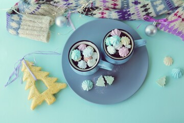 Merry Christmas, two cups of coffee, meringues, festive decor, illumination, mint color background, concept of home comfort and congratulations on winter holidays, top view, flat ley