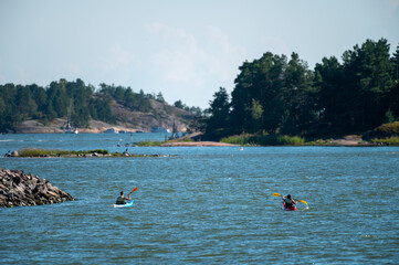 Two canoeists paddling on the shore on a sunny summer day. © Marko Hannula