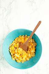 Cornflakes in blue bowl on marble background