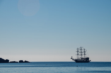 Silhouettes of a pirate ship against a blue cloudless sky