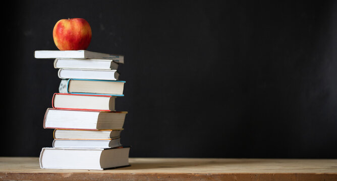 back to school concept pile of books against chalkboard