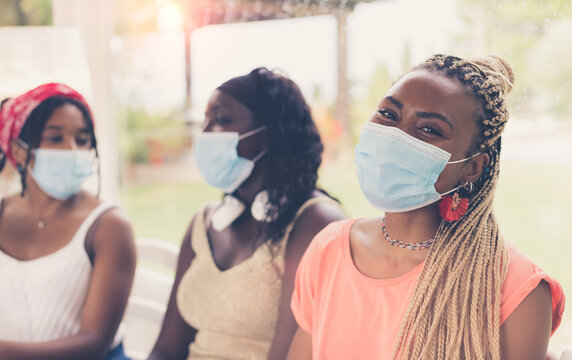 Close-up of three African American girls wearing surgical masks. 3 young women sitting together using coronavirus protection measures after or during quarantine. Concept of new normal lifestyle.