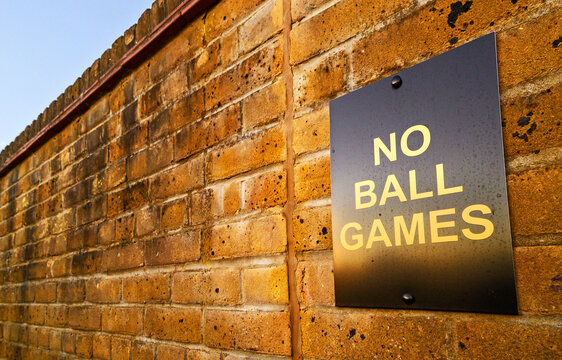 No Ball Games Sign On A Brick Wall.  No Ball Games Are Allowed On This Part Of A Residential Development. The Sign Is To Stop People Kicking Balls Against The Wall. Sign On A Wall At Sunset.