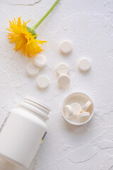 White pills and pills cantainer on a white background top view.