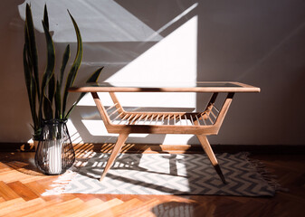 Vista frontal de pequeña mesa de madera de estilo escandinavo aislada en una habitación bien iluminada por el sol 