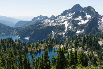 High angle view of gorgeous alpine mountain peaks surrounding lakes in evergreen valley.