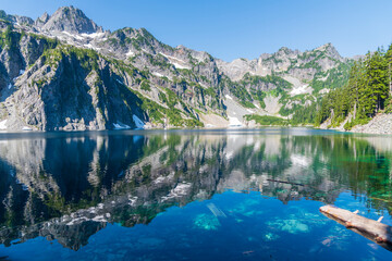 Alpine mountains reflecting into pristine placid lake in morning light. 