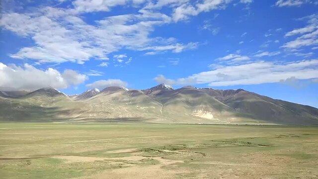 Timelapse of beautiful snow capped mountains and green fields in China