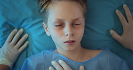 Little injured child lying on hospital stretcher while doctors transporting him to operating room. Top view of unconscious boy going on ambulance to hospital. Concept of illness - Powered by Adobe