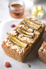Fototapeta na wymiar Loaf of Vegan Oatmeal Banana Bread topped with nut, seed, almond slide and banana set on cafe table.
