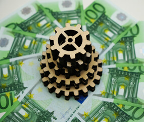many wooden gear lie on hundred euro bank notes background. time is money idea, sign, symbol,...