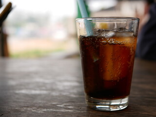 Selective focus of refreshing carbonated soft drink in a glass with ice and a straw ready to be drunk