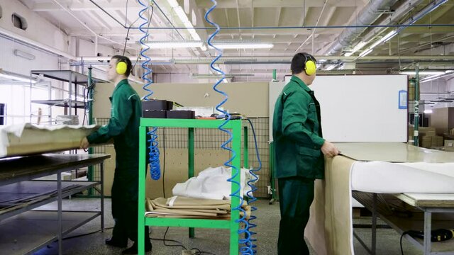 Workers dressed in uniform make a sofa, couch or settee in a furniture factory. 4K