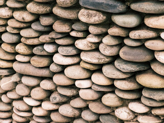Wall made of pebbles, round smooth stones. Selective focus, rough surface.