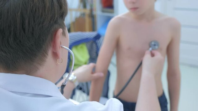 Doctor pediatrician cardiologist listening heartbeat exam of patient child boy using stethoscope on pediatric checkup appointment, children medical healthcare concept. Counting heart beats in minute.