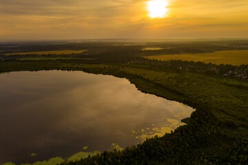 panoramic landscape of lake and forest around in summer at dawn filmed from a drone
