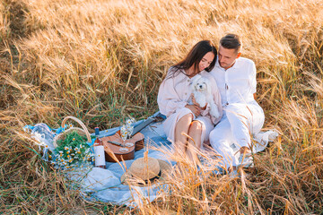 Happy young family on picnic in yellow wheat field