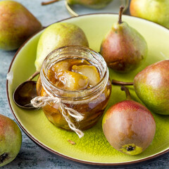 A small glass jar with homemade jam and fresh ripe pears. Selective focus.