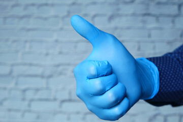 Close-up of a person hand in medical gloves showing a thumb-up.