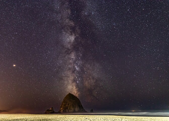 Milky Way shines in the sky behind Haystack Rock on Cannon Beach in Oregon