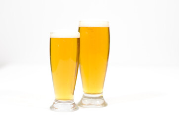 Two glasses full of beer with foam along on a white background.