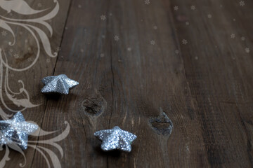 Shiny silvery Christmas stars toys on brown wooden boards. Suitable for a poster or greeting card.
