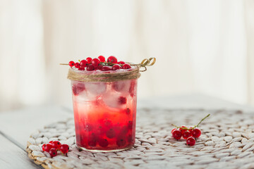 Fresh red currant cocktail in glass jar. Summer pink cocktail with red currant and ice cubes on white wooden background mockup with copy space for text.