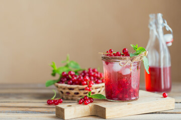 Fresh red currant cocktail in glass jar. Summer pink cocktail with red currant and ice cubes on wooden background mockup with copy space for text.