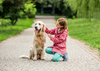Little girl with golden retriever in park
