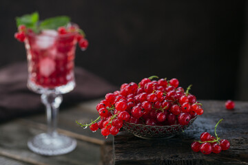 Heap of fresh red currant with water drops in a metal bowl on old dark wooden background. Healthy eating and diet food concept.