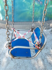 A blue child carousel seat tied with protective ribbons. Quarantine. Children's park.