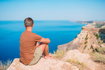 Tourist man outdoor on edge of cliff seashore