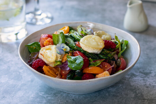 Summer panzanella salad with tomatoes, raspberries, basil and goat cheese